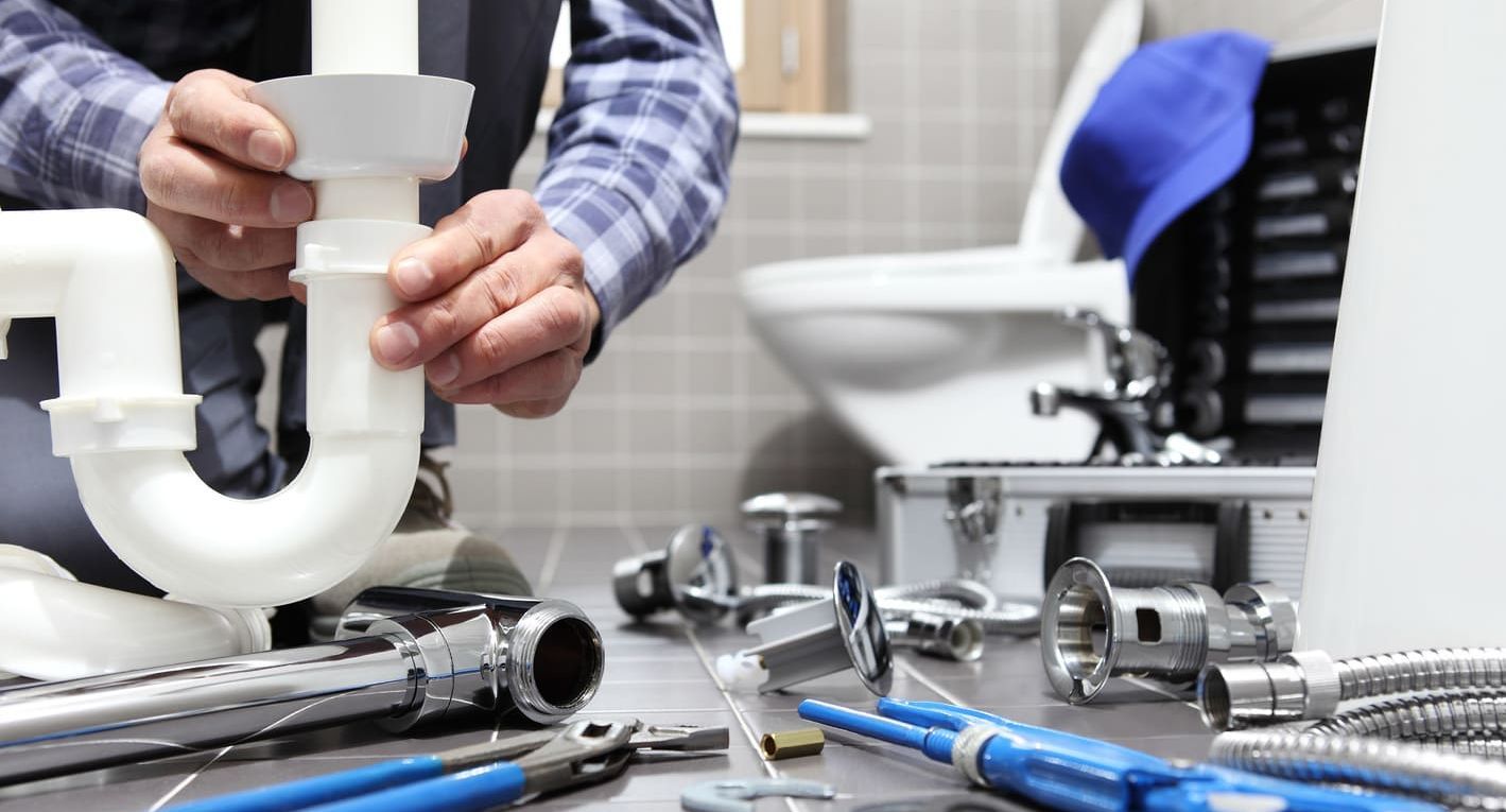 fontanero realizando reparación en baño con herramientas